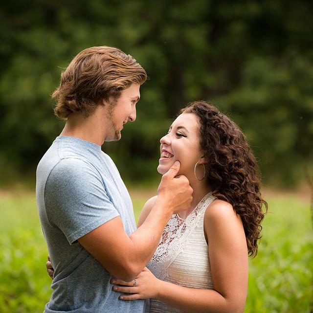 A happy couple shares a tender moment in a sun-drenched field, conveying love and connection.