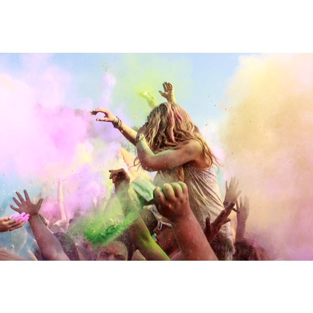 A vibrant image of a woman at a Holi festival, surrounded by a crowd and colorful powder.