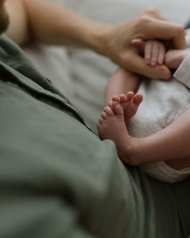 A tender moment captured in a close-up featuring a father's hand holding his baby's tiny feet, showcasing love and connection.