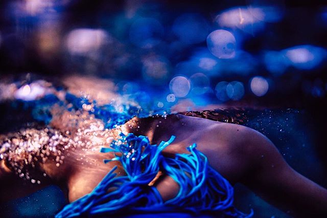 An ethereal underwater image of a woman's torso, adorned with blue accents, in a dreamlike setting.
