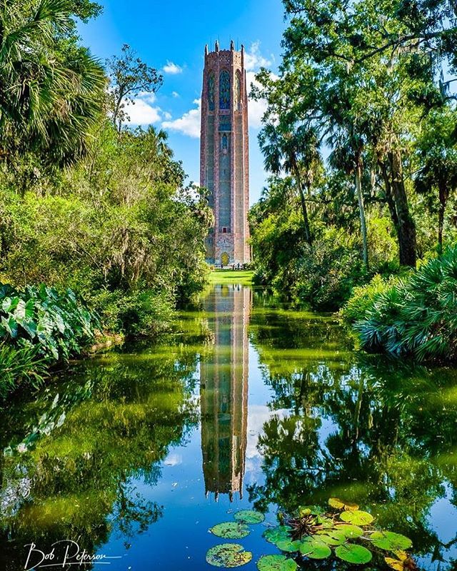 Bok Tower reflected in a tranquil pond surrounded by lush greenery in Lake Wales, Florida.