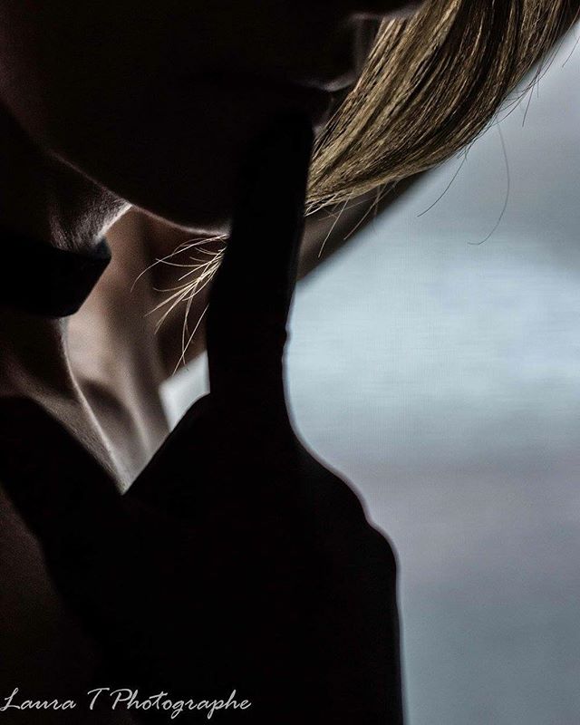 Intimate and artistic silhouette of a woman with a finger to her lips, suggesting silence.