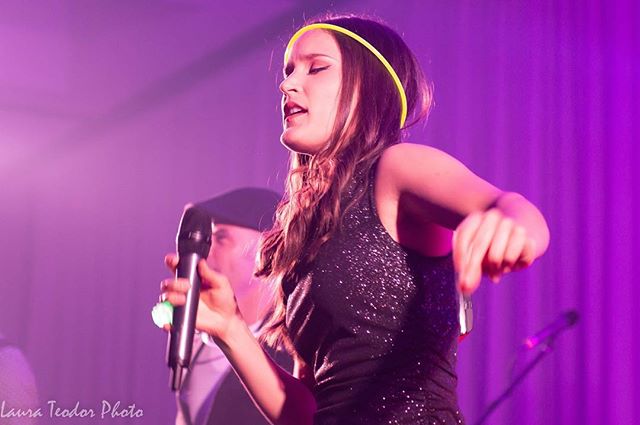 A woman sings on stage with a microphone during a live performance.