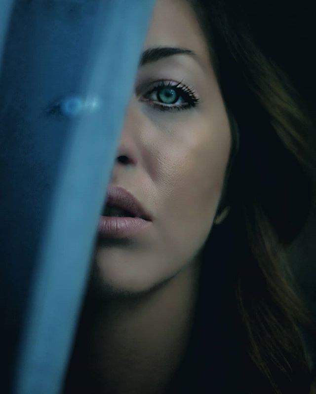 Close-up of a woman's face, partially obscured by a blue veil, emphasizing her eye and soft features.