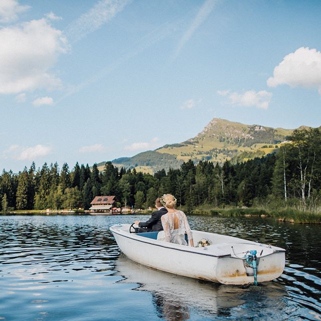 A bride and groom ride in a boat on a lake on their wedding day.