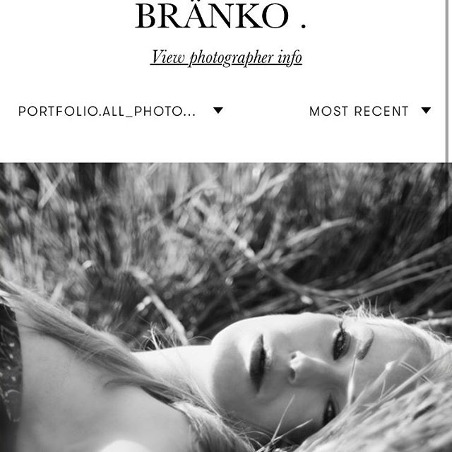 A woman lies peacefully in the grass in this black and white portrait.