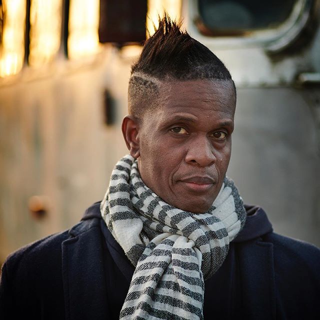 Portrait of a stylish man in a coat and scarf, with a confident expression.