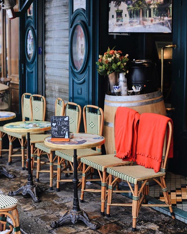 A charming outdoor cafe setup with cozy seating and a 'Hot Wine' sign, perfect for a relaxing urban scene.