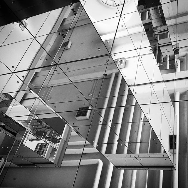 Abstract black and white architectural ceiling reflection with triangle mirrors creating a distorted perspective.