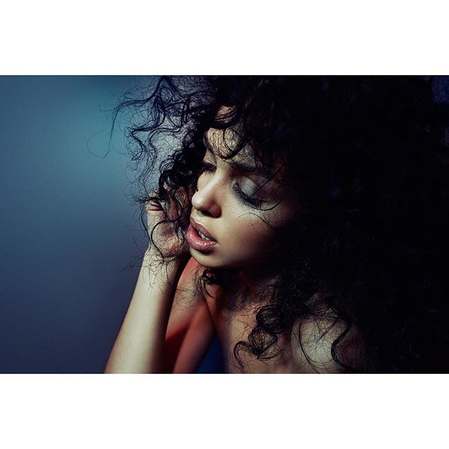 A woman with curly hair poses in a dreamy, sensual portrait for editorial and beauty campaigns.