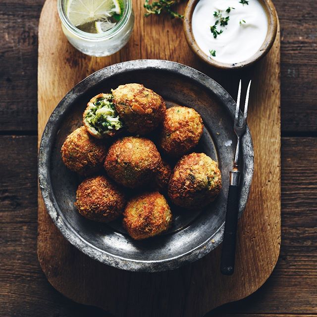 A rustic display of falafel on a metal plate with dip and lime, perfect for healthy eating campaigns.