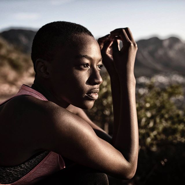 A woman pauses during an outdoor adventure, embodying strength and determination in a serene mountain setting.