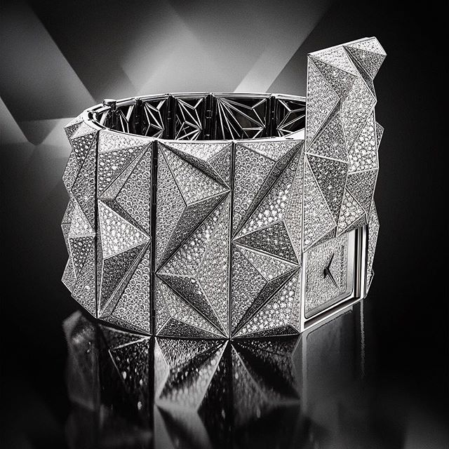 A luxurious diamond-encrusted watch is displayed in a studio with soft lighting, showcasing its elegant and opulent design.