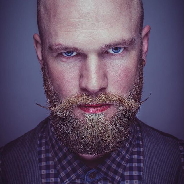 Portrait of a confident man with a styled beard, captured in a modern vintage style.