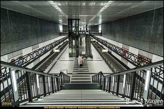 A modern subway station featuring stairs, an escalator, and empty train tracks. Clean and architectural design.