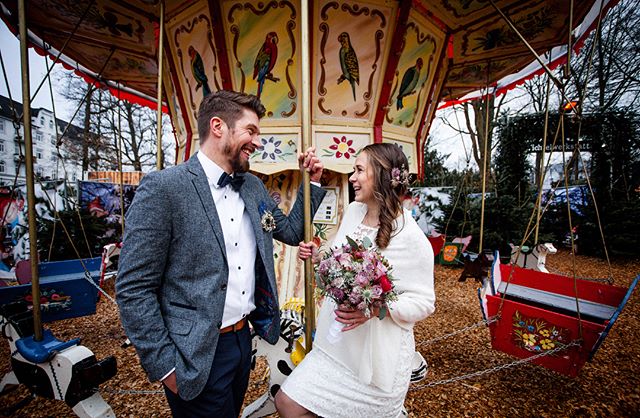 A bride and groom share a happy moment on a colorful carousel after their wedding.