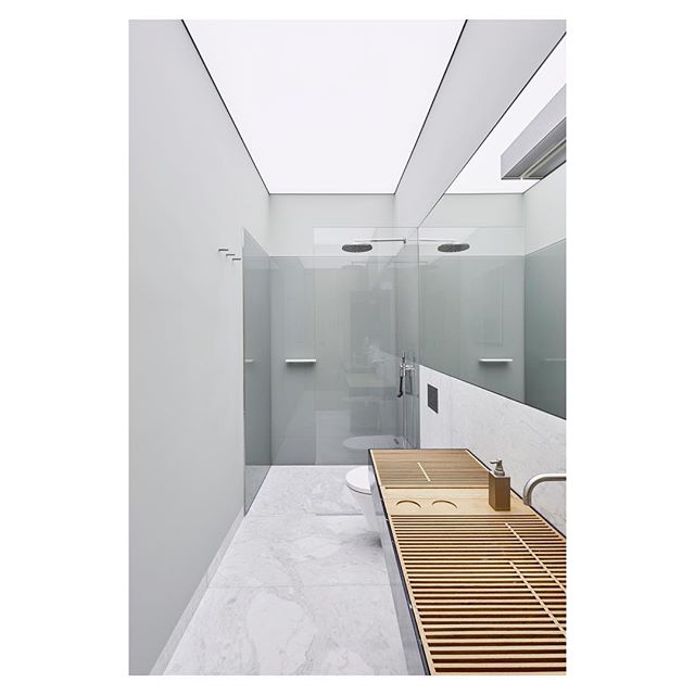 A modern minimalist bathroom features a shower, sink, toilet, and mirror for a clean, tranquil design.