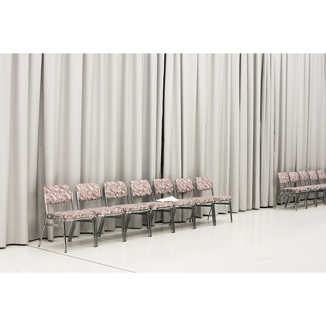 Rows of patterned chairs line a blank room with a clean aesthetic and backdrop, perfect for event marketing.