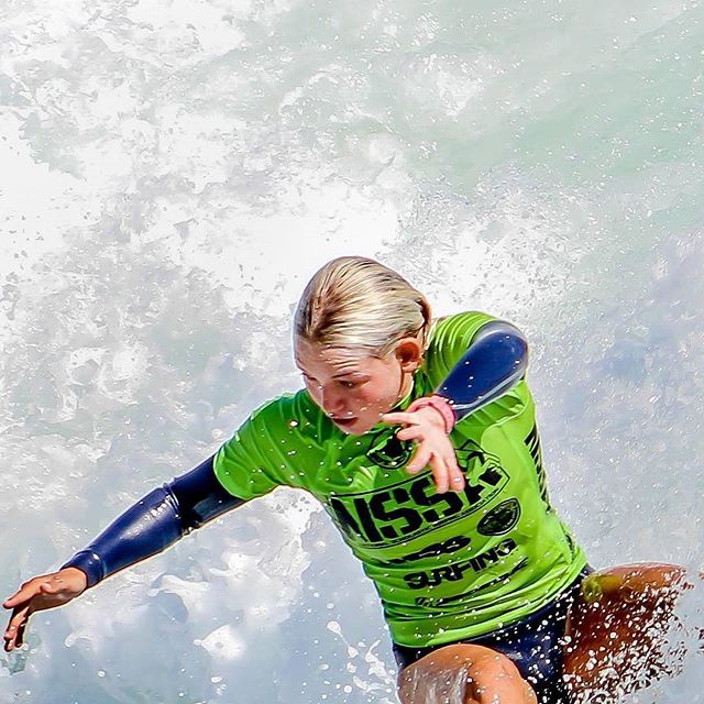 A female surfer is shown surfing in the ocean in a dynamic, high-energy moment.