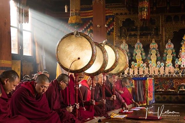 Monks in a temple are participating in a religious ceremony with large drums during a peaceful practice.