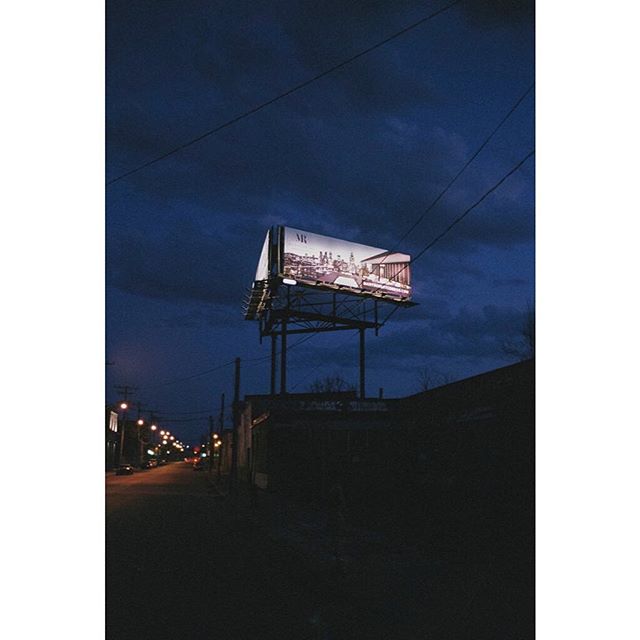 A billboard illuminates a dimly lit city street at night, casting light on the surrounding buildings.