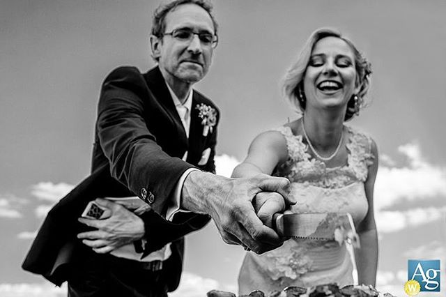 A bride and groom share a happy moment cutting their wedding cake in a black and white shot.