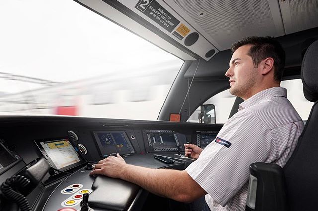 A focused train driver operates the control panel of a modern train.