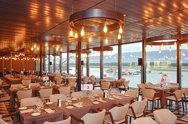 Elegant restaurant with tables set for a meal, with a view of the airport runway.