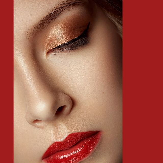 Close-up of a woman's face with red lipstick and golden eyeshadow in an elegant beauty shot. The image is great for beauty advertisements.