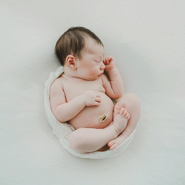A newborn baby sleeps peacefully wrapped in a soft, white blanket, creating a serene and tender moment.