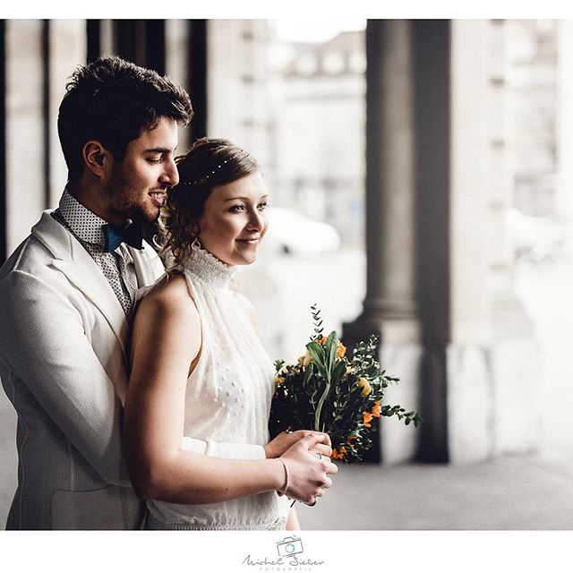 A bride and groom share an intimate moment on their wedding day in an urban setting.