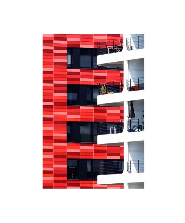 Exterior view of a modern building with red tile and white balconies. Modern architecture.