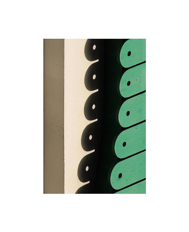 Abstract close-up of a green wooden fence with light and shadow patterns. Simple and aesthetic.