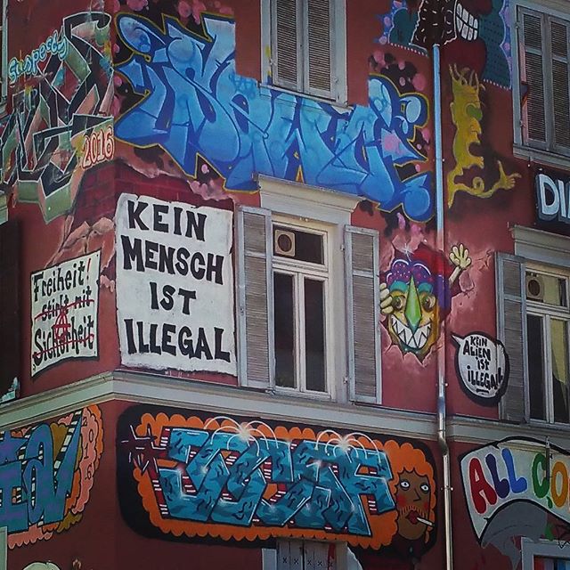 A building with colorful graffiti and political messages advocating for human rights and social justice.