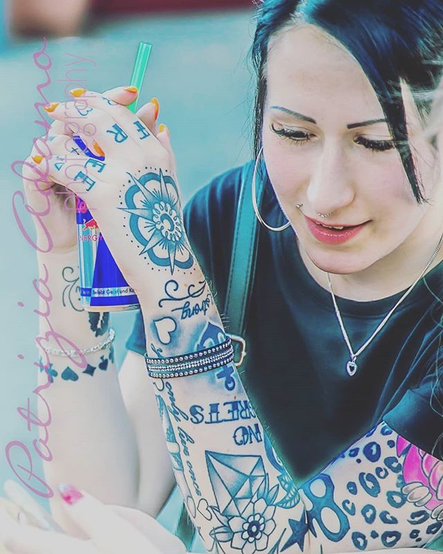 A tattooed woman sips a drink. The image promotes youth and a casual lifestyle.