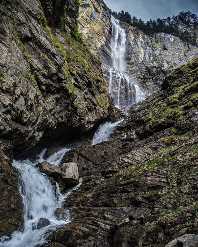 A scenic waterfall cascades down a rocky mountain, offering a tranquil natural landscape.