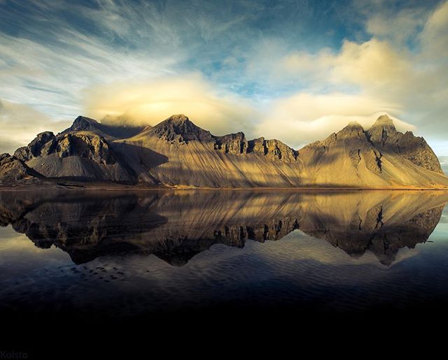 A stunning landscape featuring mountains reflecting in calm water in Iceland.