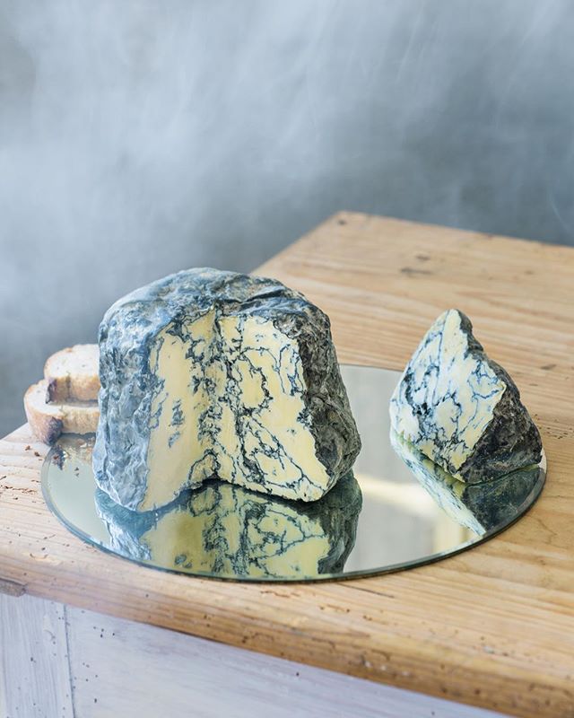 Close-up of blue cheese and bread on a mirror, reflecting the light.