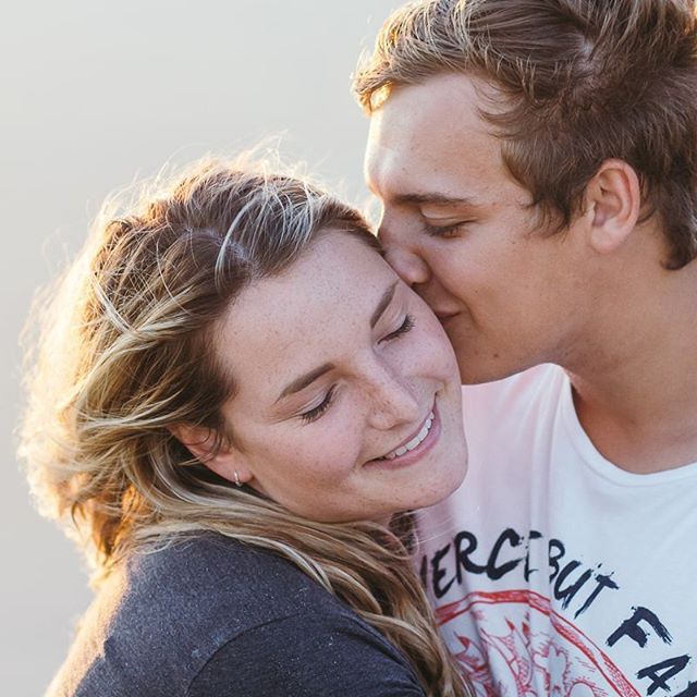 A young couple shares a tender moment, the man kissing the woman's cheek in a loving embrace.