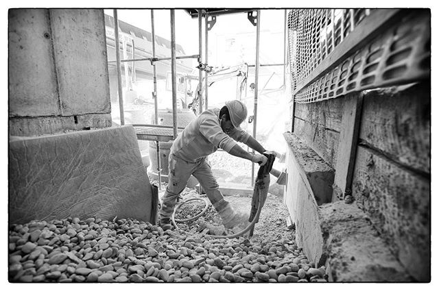 A construction worker uses a jackhammer at a construction site, working on the walls of the building.