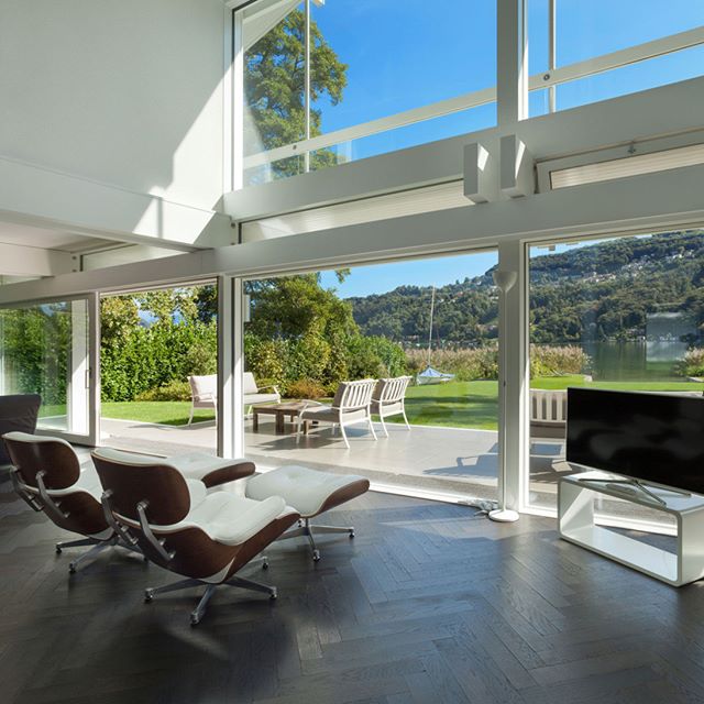Bright modern living room with lake view, featuring stylish chairs and contemporary design, perfect for real estate or interior design.