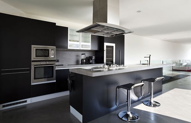 A modern kitchen features a sleek island with stools and stainless steel appliances.
