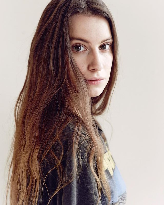 A young woman gazes directly at the camera in a soft, intimate portrait.