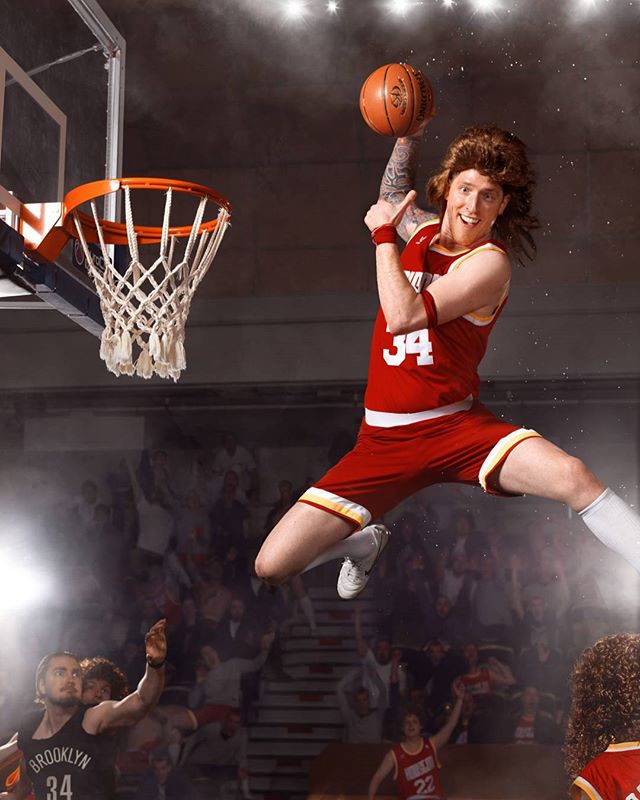 An energetic basketball player performs a slam dunk in a vibrant arena.