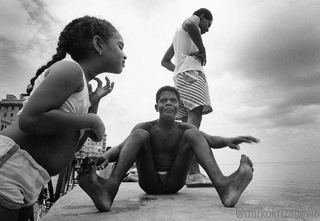 Three children are enjoying the waterfront in a black and white image.