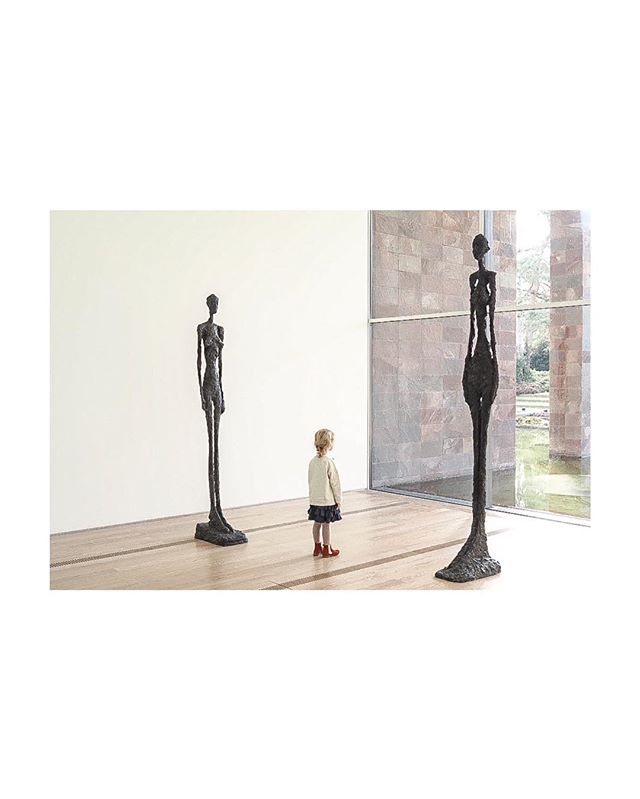 A child views two bronze sculptures in an art gallery, showcasing modern art and cultural experiences.