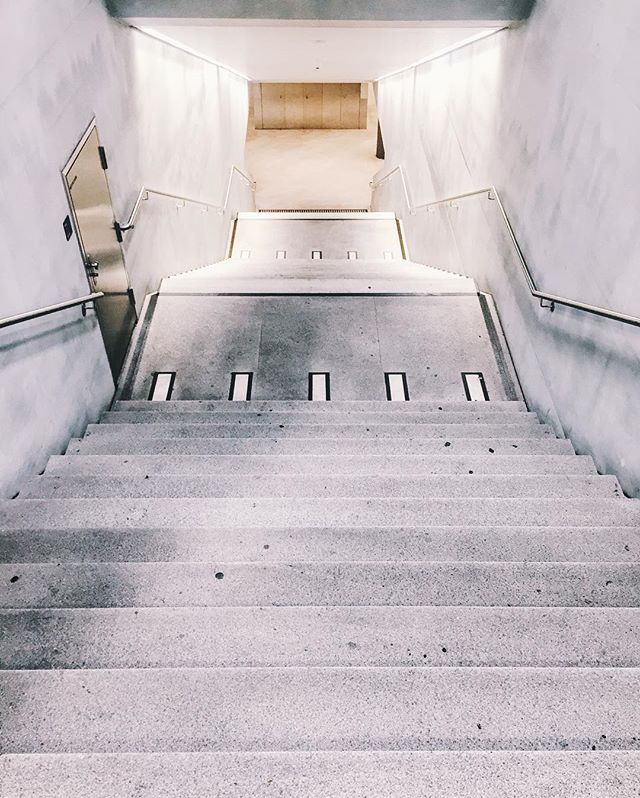 A minimalist stairway leads down into a modern building, featuring clean lines and neutral colors. Ideal for architecture and design content.