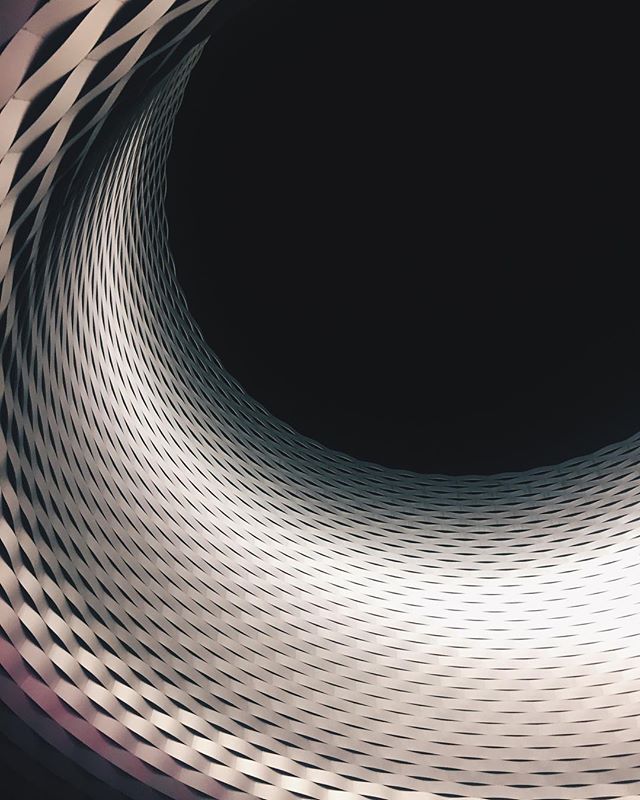 Abstract architectural interior featuring a repeating curved pattern against a dark void.