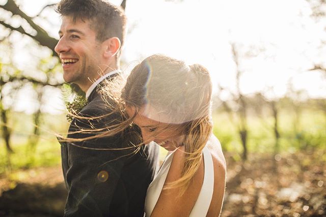 A happy couple shares an intimate moment during their wedding day in a sun-drenched forest. 