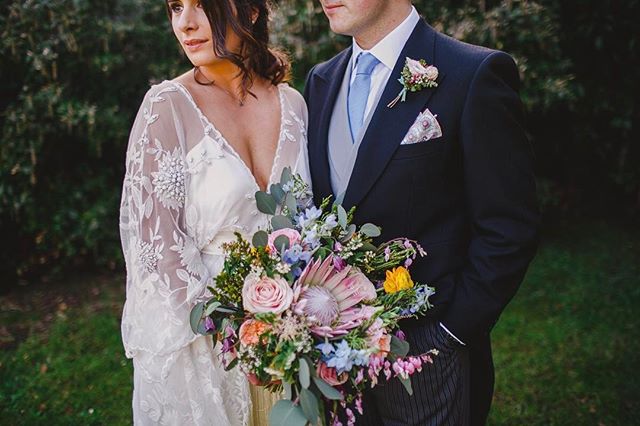 A bride and groom pose with a colorful bouquet at their wedding, exuding romance and elegance.
